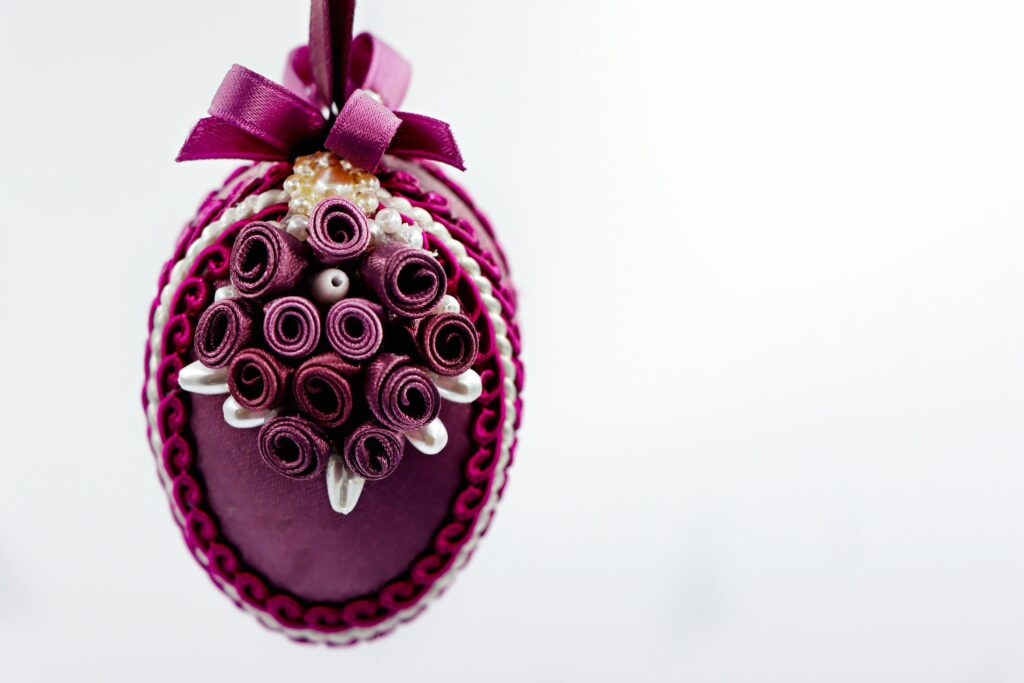 Artistic Easter egg decoration with intricate purple designs and a bow, perfect for spring decor.